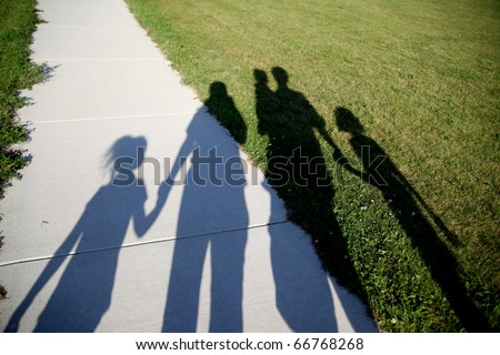 Shadows of a family of five walking in the park holding hands