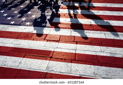 Shadows Of Group Of People Walking Through The Sunny Streets With Painted United States Of America Flag On The Floor.