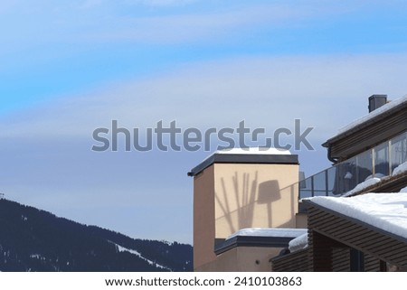 Shadows on a building on a sunny winter day against the backdrop of the mountains, a subtle combination of human activity and winter silence