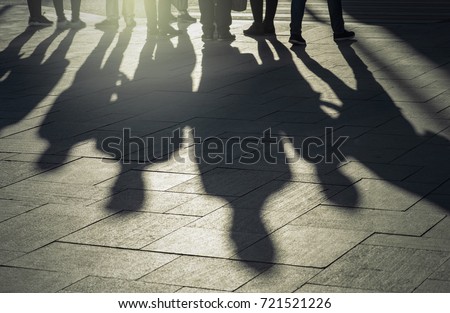 Shadows and silhouettes of people at a city during sunset