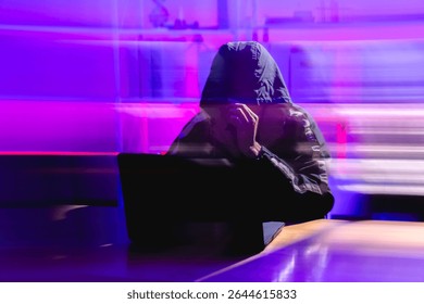 A shadowy figure works intensely on a laptop, symbolizing cybersecurity threats in cloud networks. This image illustrates the complexities and risks of modern digital attacks.