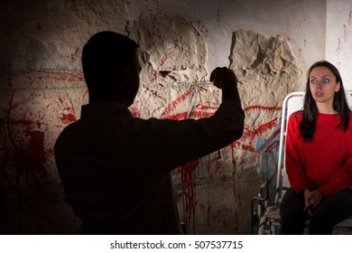 Shadowy Male Figure Pours Liquid From Beakers In Front Of Patient Near Blood Stained Wall For Concept Scary Halloween Holiday