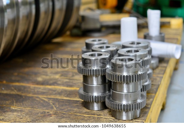 Shaft shaft, gear\
after machining on the lathe and CNC milling machine lies on a\
wooden rack in the shop.