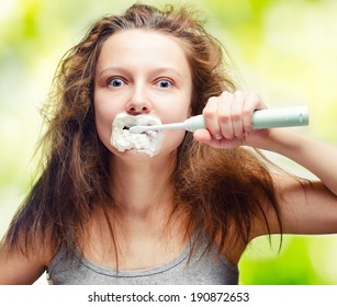 Shaggy Young Woman Using Electric Toothbrush.