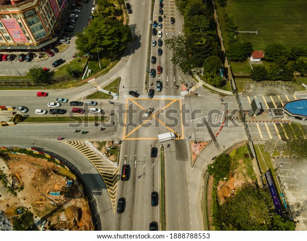 SHAH\
ALAM, MALAYSIA - JANUARY 05, 2021 : Aerial Still Photo : A high\
angle afternoon shot of a busy junction traffic light intersection\
with cars waiting for the green light in\
Malaysia.