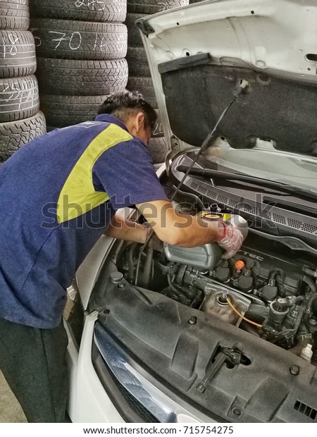 Shah Alam, Selangor AUG 1 2017 : mechanic not in
protective gear changing repairing car tire in a workshop using a
jack lifting to check break pads and safety of vehicle prior to the
holiday season