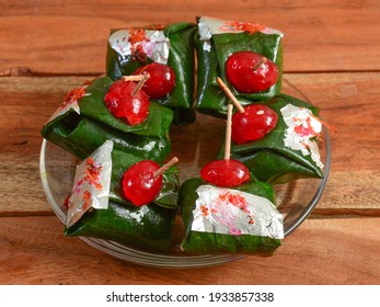 Shahi kolkatta paan, Indian Traditional Mouth Freshener wrapped in betel leaf, often used as an after dinner digestive. served over a white plate on a rustic wooden background, selective focus