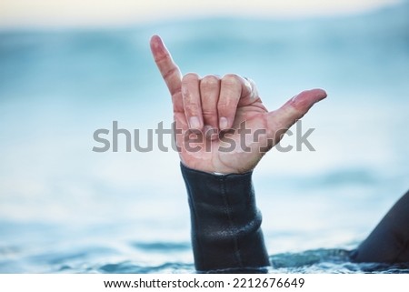 Shaka, surf and man in ocean with hand sign outdoor in nature while on vacation in Australia. Surfing culture, hang loose gesture and closeup of hands of friendly surfer in water at beach on holiday.