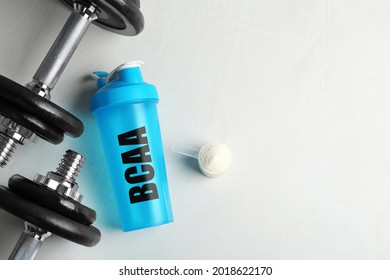 Shaker With Abbreviation BCAA (Branched-chain Amino Acid), Dumbbells And Powder On White Table, Flat Lay. Space For Text