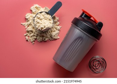 Shaker and protein powder on pink background. Sports nutrition concept