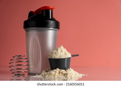 Shaker and protein powder on pink background. Sports nutrition concept.