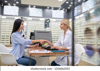 Shaking Hand. Beautiful Young Woman Wearing Jeans And Blouse Shaking Hand Of Eye Doctor