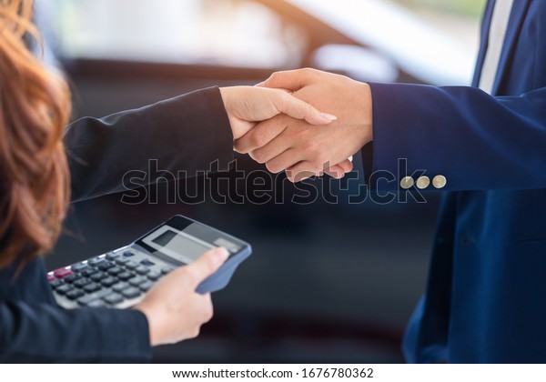 [shaking hands in auto show] auto\
business, car sale, deal, gesture and people concept, buy new cars\
that make sales agreements with car dealers at car\
dealers.