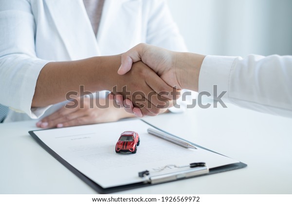 shaking hands, Car dealership provides\
advice about insurance details and car rental information and\
delivers the keys after signing the rental\
contract.