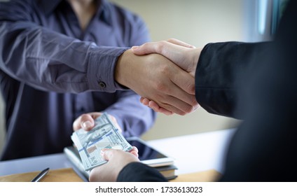 Shaking hands with congratulations on an evil plan, Businessmen give dollars to bribe employees in signing contracts to buy illegal land and real estate, corruption and Bribery concept, - Shutterstock ID 1733613023