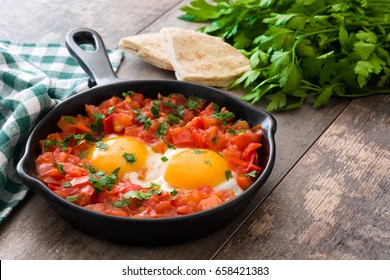 Shakshuka In Iron Frying Pan On Wooden Table. Typical Food In Israel.
