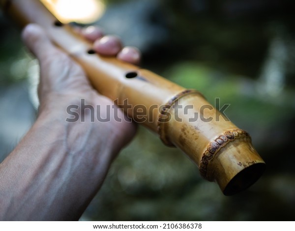 Shakuhachi. Flute made of bamboo.\
Outdoors. It\'s in the guy\'s hand. Man\'s hands. With natural\
pattern. Tool\
demonstration.