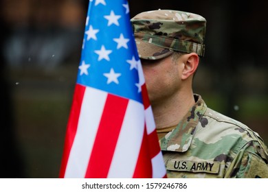 Shallow Depth Of Field Image (selective Focus) With Details Of A US Army Soldier Holding A USA Flag And Having MNDSE (Multi-National Division South-East) Insignia.