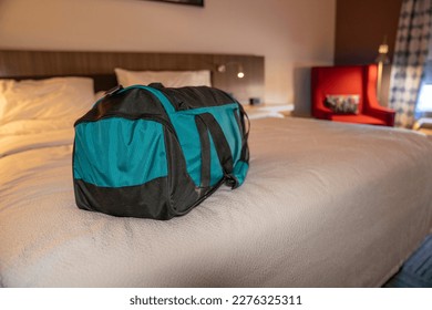 Shallow depth of field image of a small travel bag on the bed of a hotel room