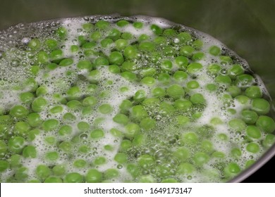 Shallow depth of field image of some peas in boiling water with steam coming from them. Could be used to show how to boil frozen garden peas.