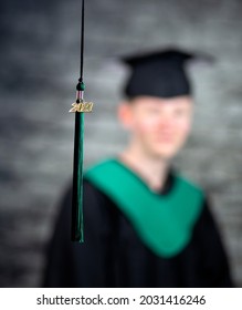 Shallow Depth Of Field Image With A Young Male Wearing A Cap And Gown Slightly Blurred With A 2021 Gold Symbol In The Foreground In Focus.