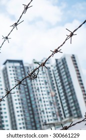 Shallow depth of field, old bared steel wire against blue sky with blurred modern buildings