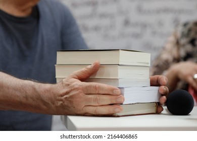 Shallow Depth Of Field (selective Focus) Details With The Hands Of A Man On A Pile Of Books During A Book Release Event.