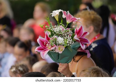 Shallow Depth Of Field (selective Focus) Details With A Woman Holding Flowers During The First Day Of School For Her Child.