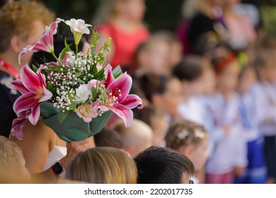 Shallow Depth Of Field (selective Focus) Details With A Woman Holding Flowers During The First Day Of School For Her Child.