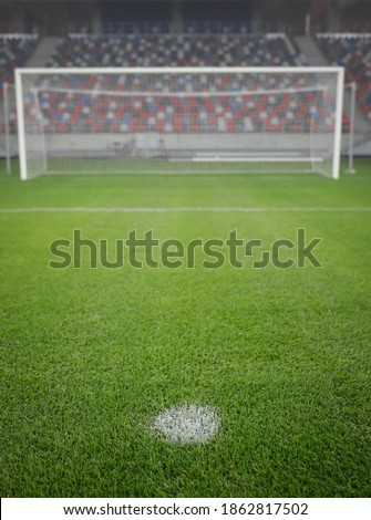 Shallow depth of field (selective focus) image with the penalty kick point on an empty soccer stadium.