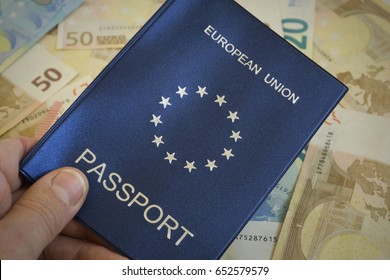 Shallow Depth Of Field Shot Of Man An Holding European Union Passport Against Backdrop Of Euro Notes