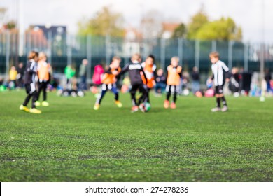 Shallow depth of field shot of young boys playing a kids soccer match on green turf.
