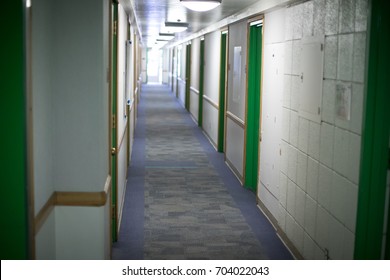 Shallow Depth Of Field View Down An Empty College Dormitory Hallway With Green Door Frames