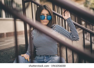 A Shallow F Of A Cool, Fashionable Teenager With Blue Sunglasses Sitting On An Apartment Front Steps