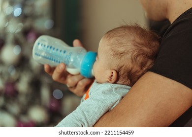 A Shallow Focus Of An Adult Woman Feeding A Child Milk From A Bottle