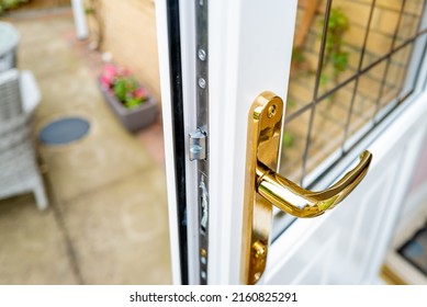 Shallow Focus Of The Brass Coloured Door Handle On A Newly Installed Double Glazed Door. Showing The Leaded Window, Leading Out Onto A Patio Area.