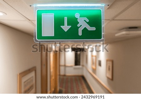 Shallow focus of a generic Fire Escape sign seen hanging from the ceiling of a hotel lobby in the UK.