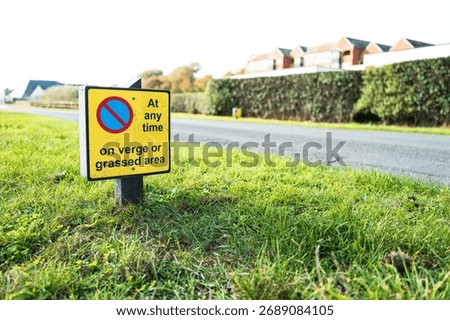 Shallow focus of a ground level No Waiting or Parking sign seen on a grassy verge near the access road of the British seaside town of Aldeburgh, Suffolk. 