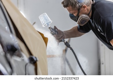 A shallow focus of a man spray painting a car in spray-painting booth