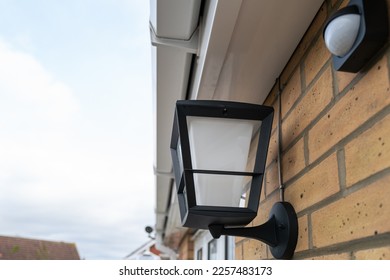 Shallow focus of a newly installed, multi colour smart lighting lantern outside the rear door of a house. A nearby PIR sensor is also seen. - Shutterstock ID 2257483173