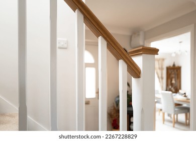 Shallow focus of a newly installed wooden banister seen near a porch and open dining room. Located at a show home.