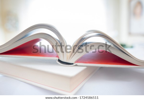 Shallow focus on open book in\
home environment. Focus on spine of book. Unfocused home\
environment