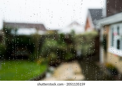shallow focus of rain droplets seen on a conservatory double glazed window looking out to a patio area.