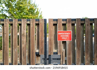 Shallow focus of a red Emergency Access Sign seen on a gated entrance to a hospital facility.