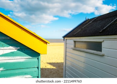 Shallow Focus Of A Repaired, Wooden Beach Hut Showing Wood Filler Being Applied To The Brightly Painted Wooden Panels. A Distance Suffolk Beach And North Sea Can Be Seen.