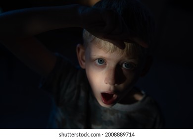 A Shallow Focus Of A Scared Blue-eyed Child Looking Up Against A Dark Background - Concept Of Child Abuse