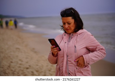 A Shallow Focus Shot Of A Caucasian Woman Checking Her Phone At A Beach On A Cloudy Day 