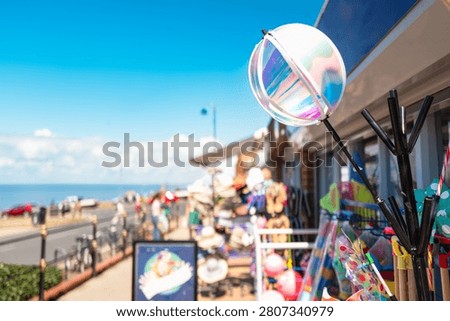 Shallow focus of a spherical wind spinner seen for sale together with other beach items at a typical toy and souvenir shop on the British coast. In the distance is the beach and North Sea.