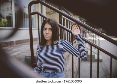 A Shallow Focus Of A Teenager In A Black And White Long Sleeved Shirt Sitting On An Apartment Front Steps