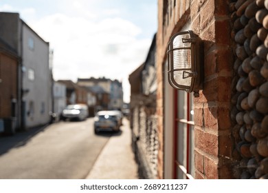 Shallow focus of a typical bulkhead light seen at the entrance to a front terraced house in England. Parking is a problem due to how narrow the street is.